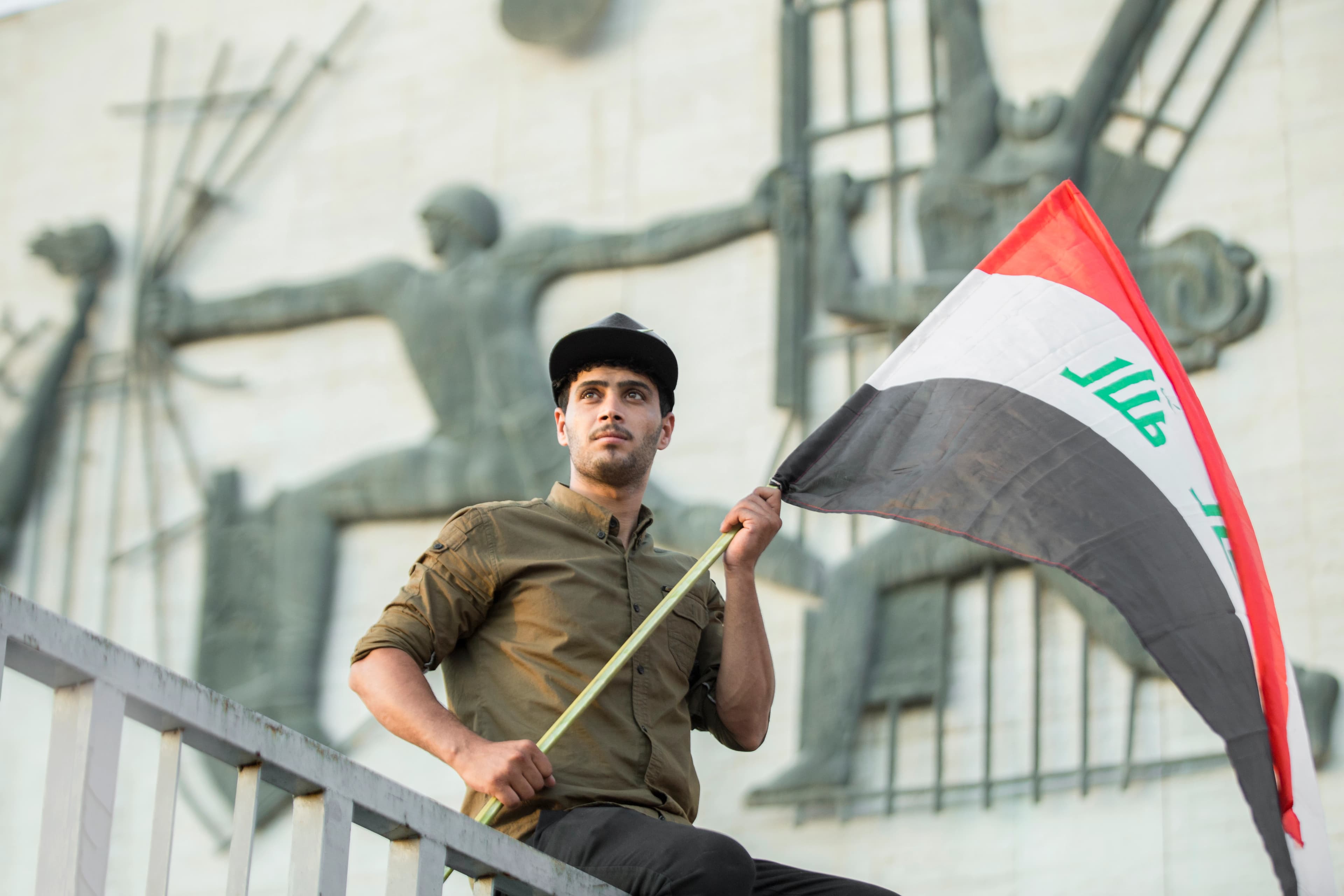 شاب يحمل علم العراق في ساحة التحرير بالعاصمة بغداد